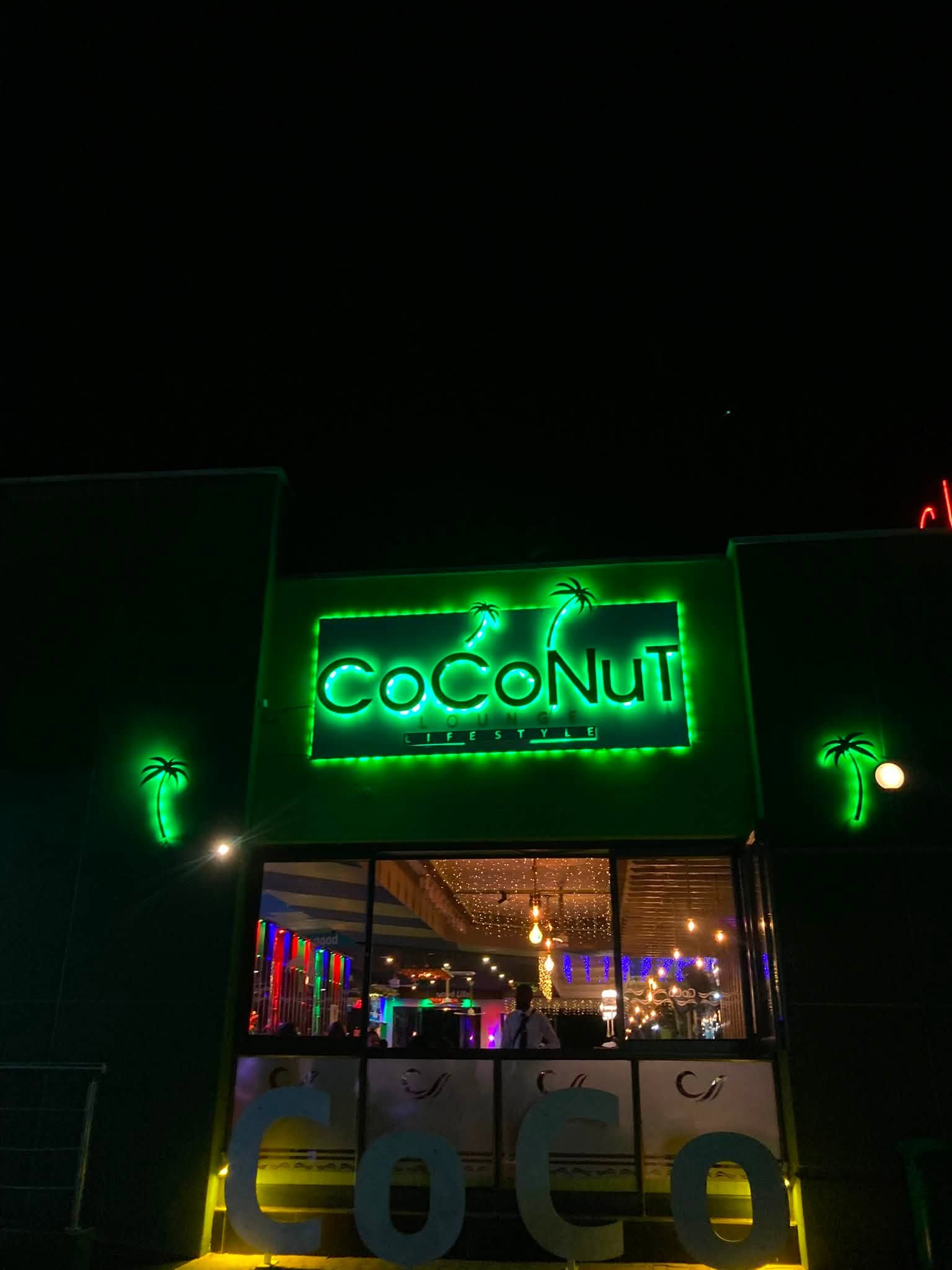 Coconut Lounge sign glowing at night over the entrance